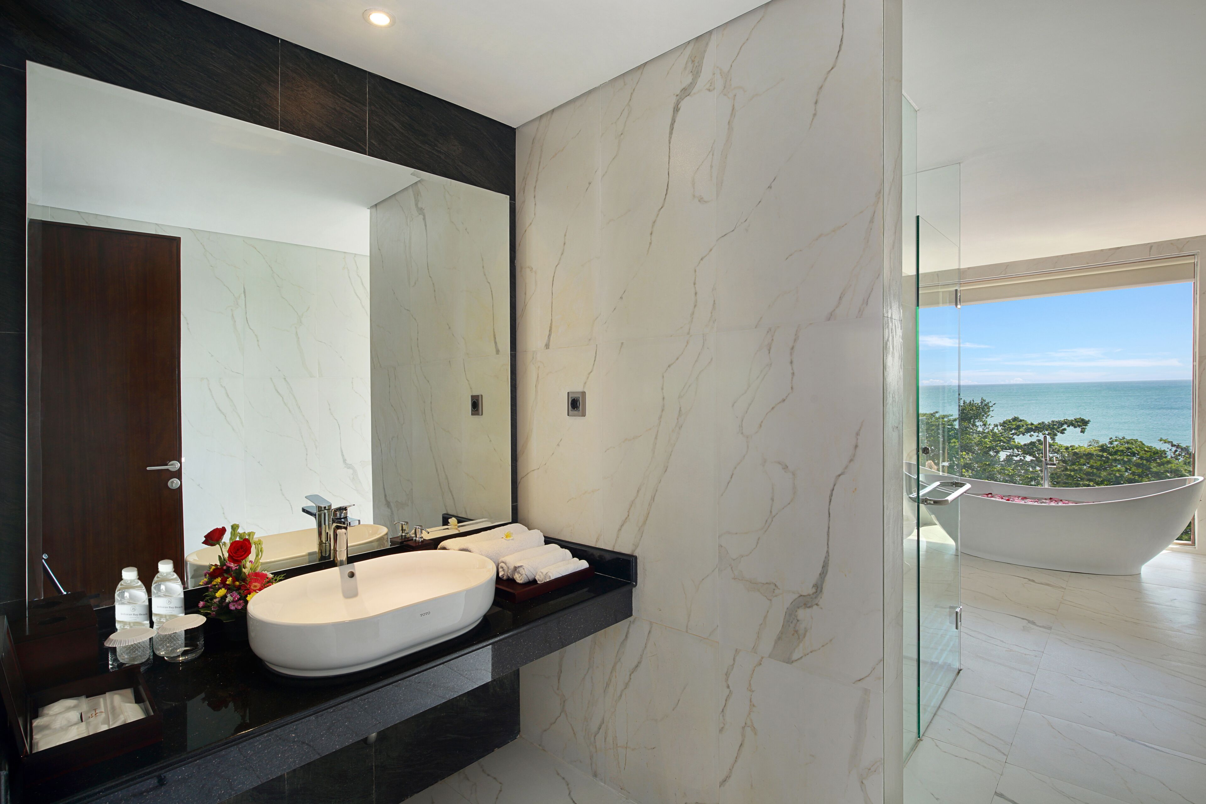 A modern bathroom with a large mirror, a white sink, and a bathtub.