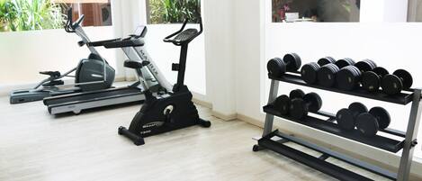 A home gym with a treadmill, elliptical, and dumbbells.