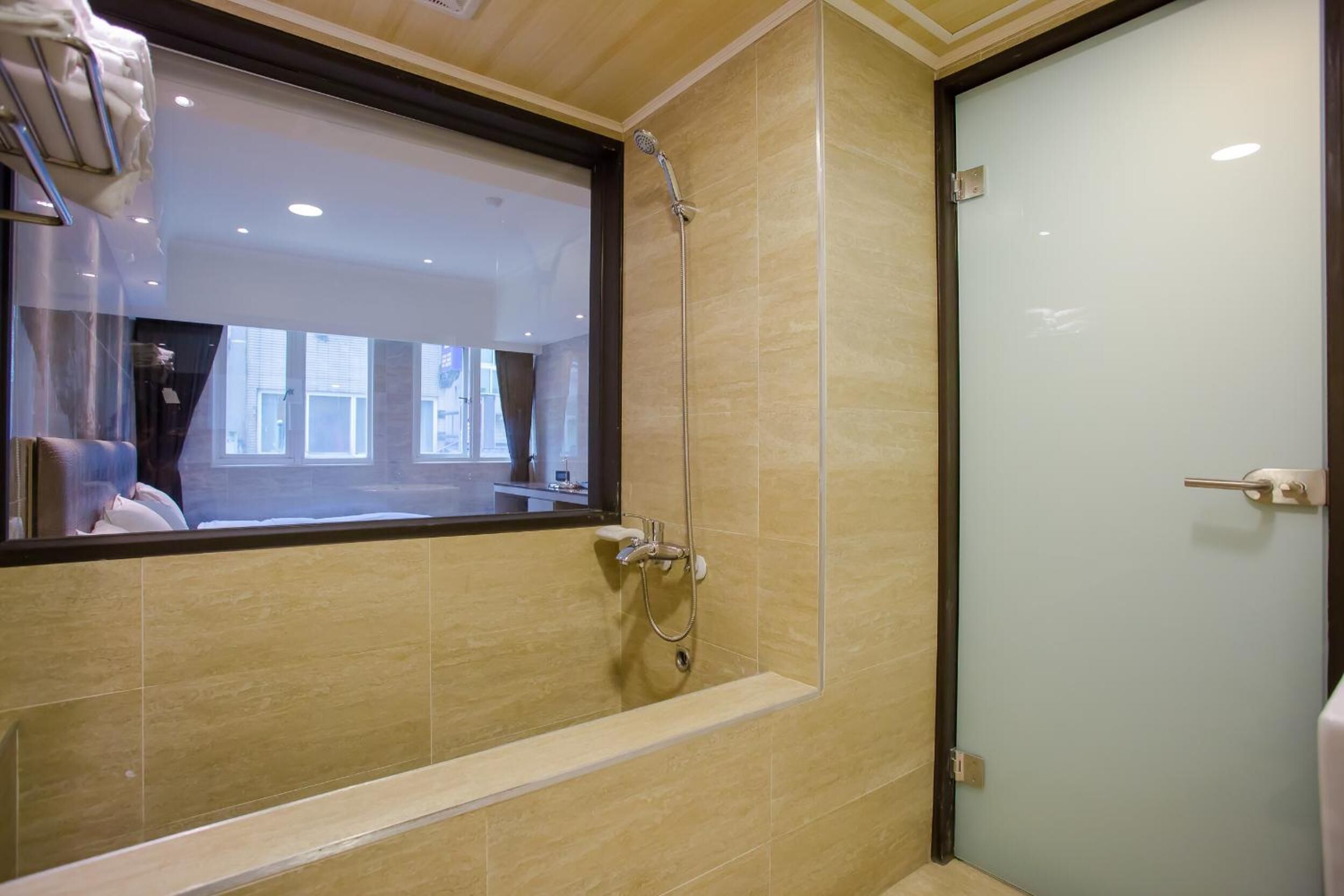 A modern bathroom with a glass shower enclosure, a large mirror, and a view of the outside.
