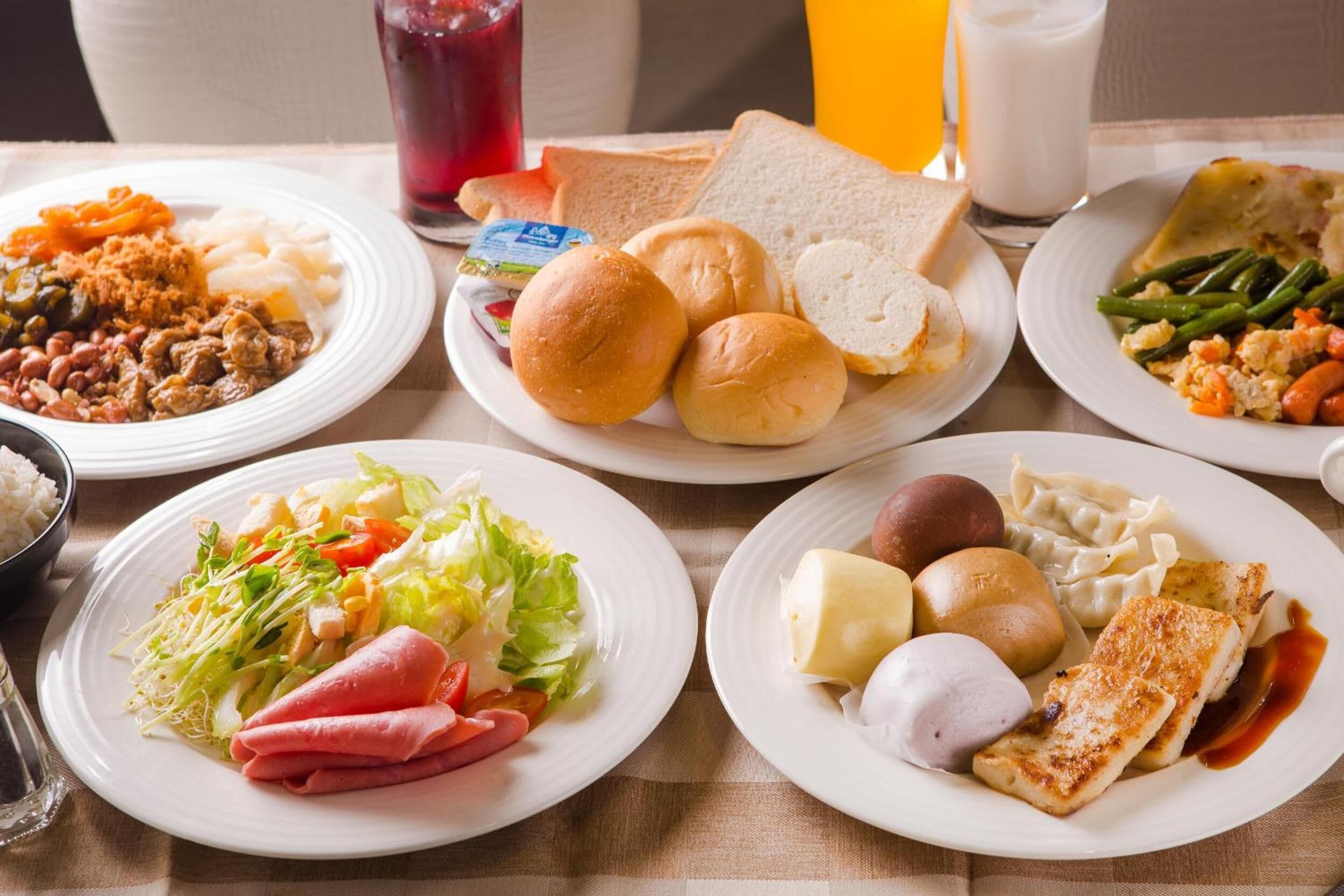 A table with various dishes including bread, vegetables, and a salad.