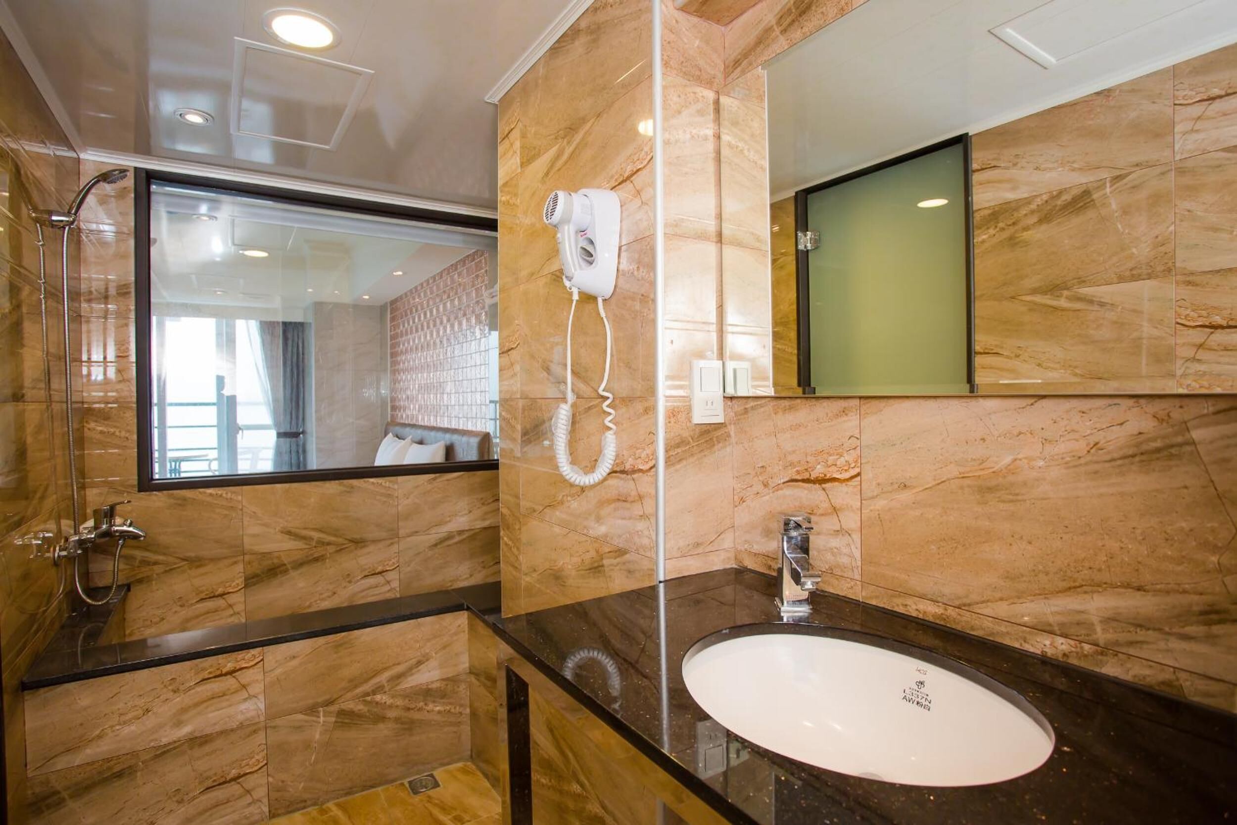 A modern bathroom with a marble vanity, a sink, a hairdryer, and a shower.