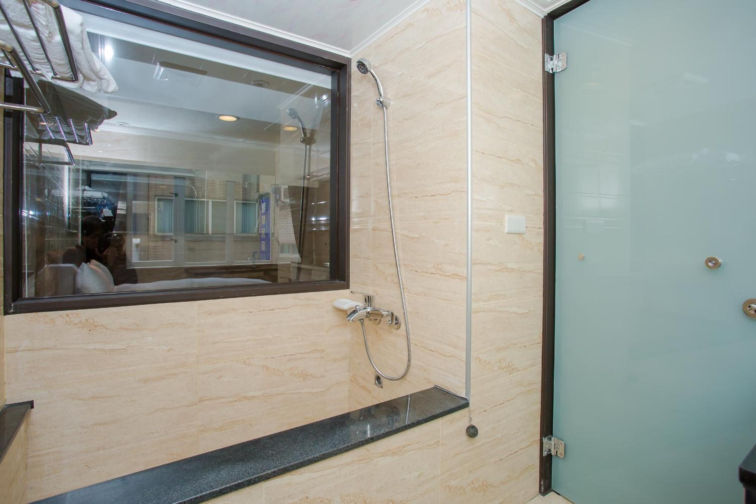 A bathroom with a glass shower enclosure, a mirror, and a sink.