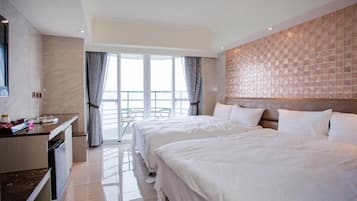 A hotel room with two beds, a kitchenette, and a balcony with a view.