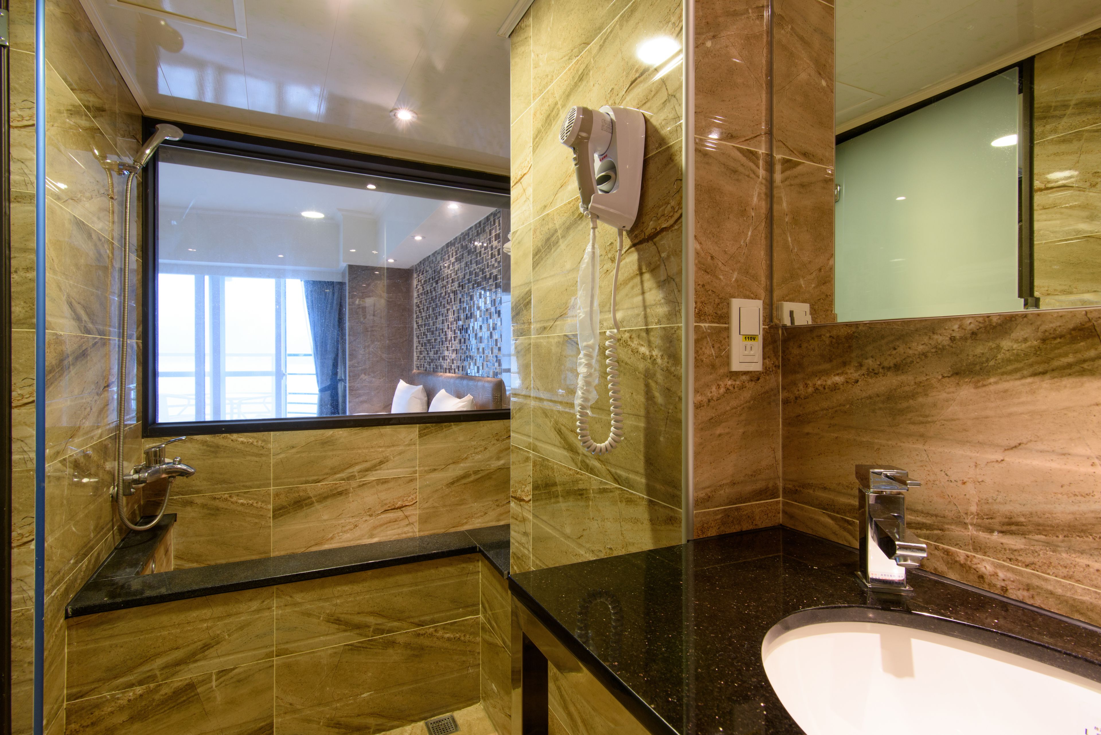 Un baño moderno con un espejo grande, un secador de pelo, un lavabo y una zona de ducha.