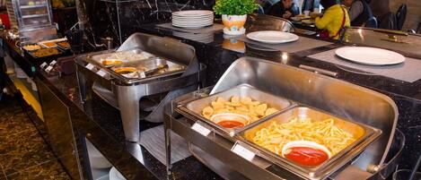 Un espace buffet proposant une variété de plats, notamment des frites et d’autres mets, dans un cadre intérieur bien éclairé.