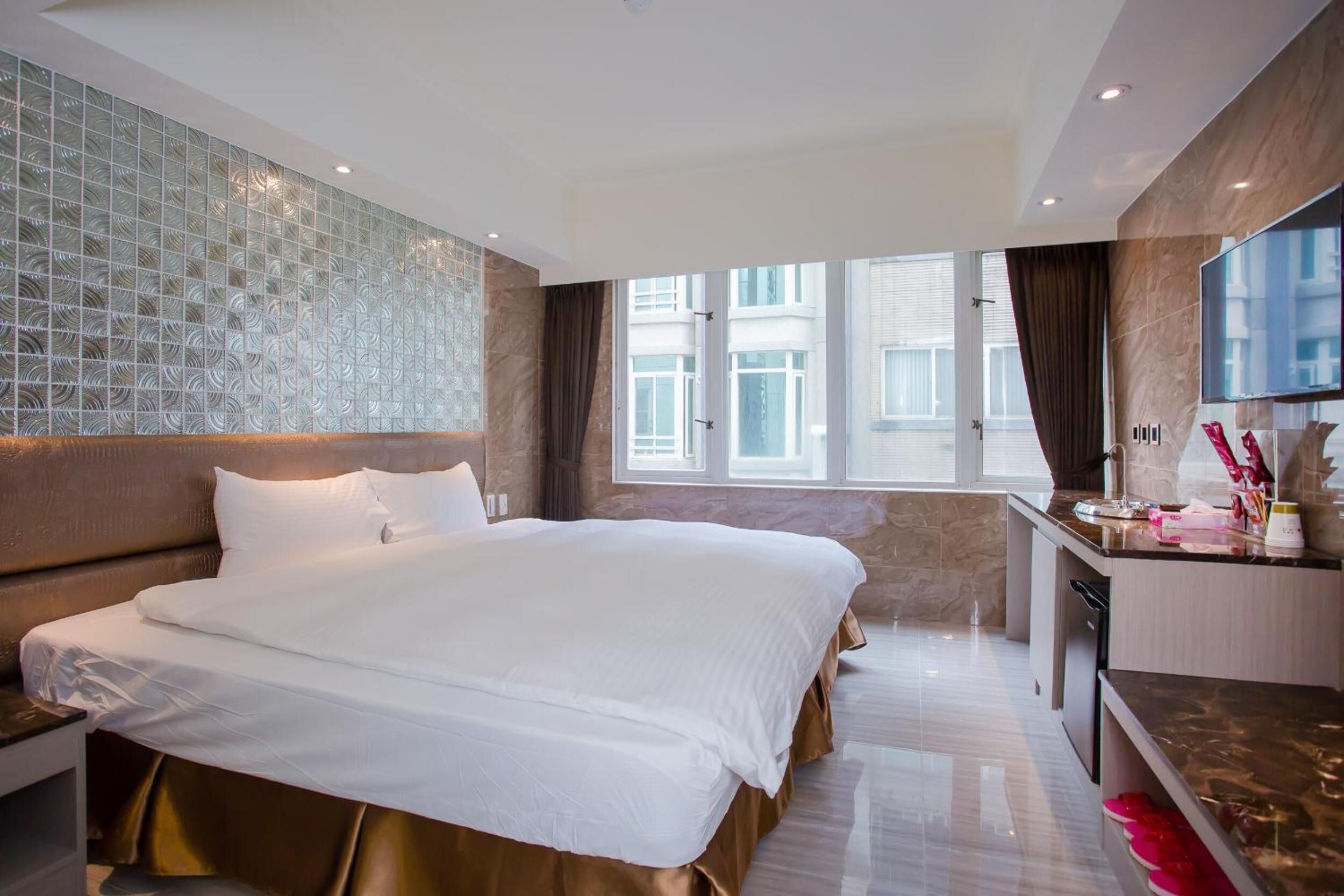 A modern hotel room with a large bed, a desk, and a TV.