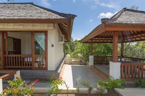 A two-story building with a tiled roof, large windows, and a covered outdoor area with a wooden deck. - Villa Lidwina by Nagisa Bali (Ungasan)