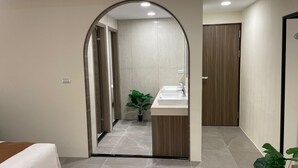 Un baño moderno con tocador, una planta en maceta y una puerta de madera.
