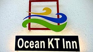 Un letrero del Ocean KT Inn con un logotipo colorido y el nombre en letras blancas sobre fondo negro.