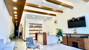 Un área de recepción moderna con un televisor de pantalla plana, armarios de madera y una silla azul.