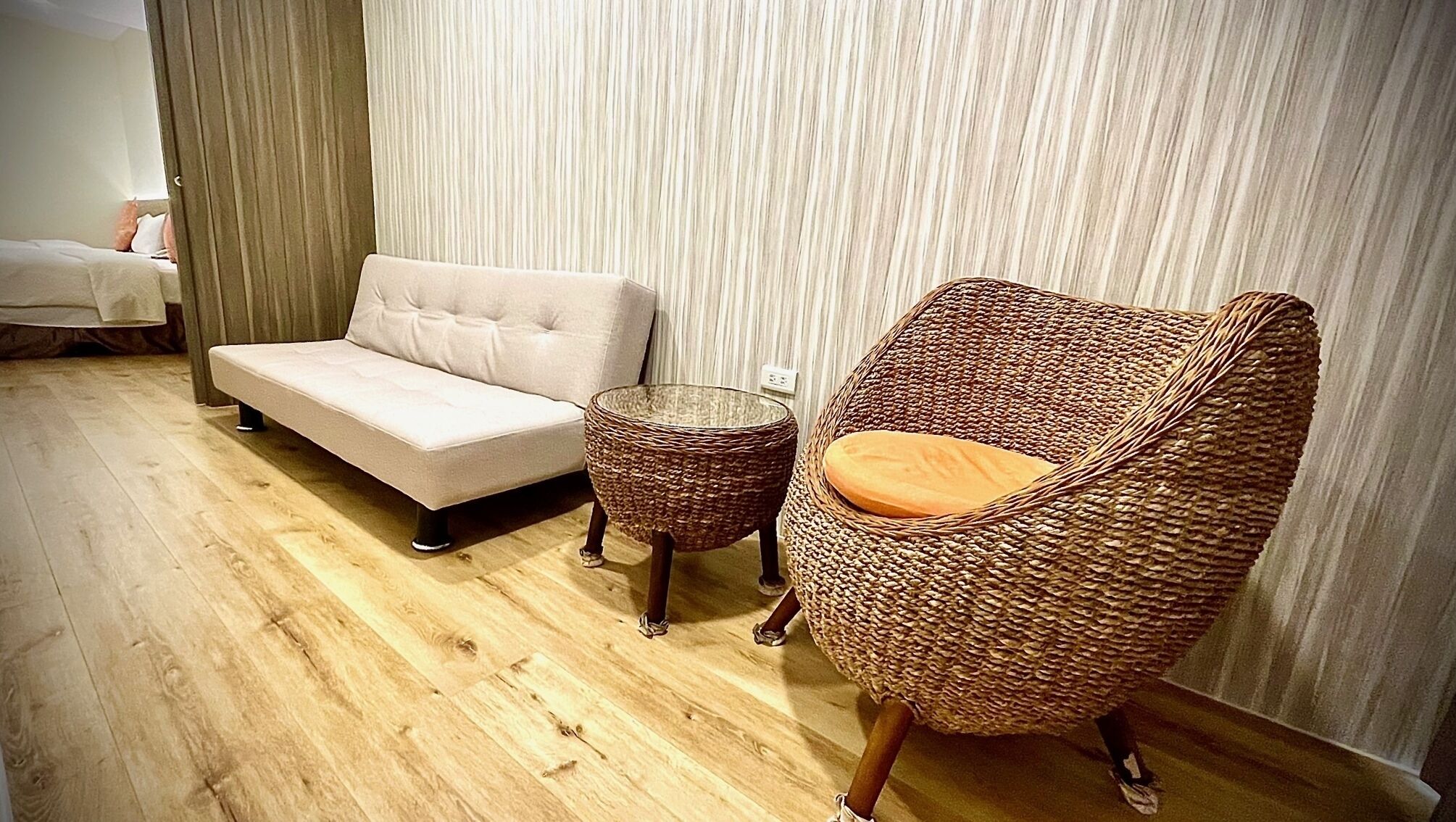 Una sala moderna con un sofá, un sillón de mimbre y una pequeña mesa redonda.