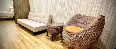 Una sala moderna con un sofá, un sillón de mimbre y una pequeña mesa redonda.