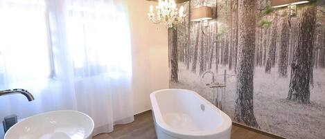 Une salle de bain dotée d’une baignoire sur pieds, d’un lavabo en forme de vasque et d’une fresque murale sur le thème de la forêt.