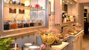 Un espace buffet proposant une variété de plats, notamment un grand saladier rempli de fruits et des pots de confitures.