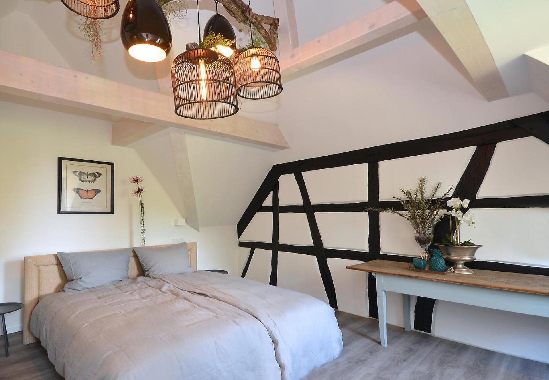 A bedroom with a bed, a desk, and a large window with black framing.