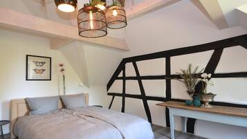 Ein Schlafzimmer mit Bett, Schreibtisch und einem großen Fenster mit schwarzem Rahmen.