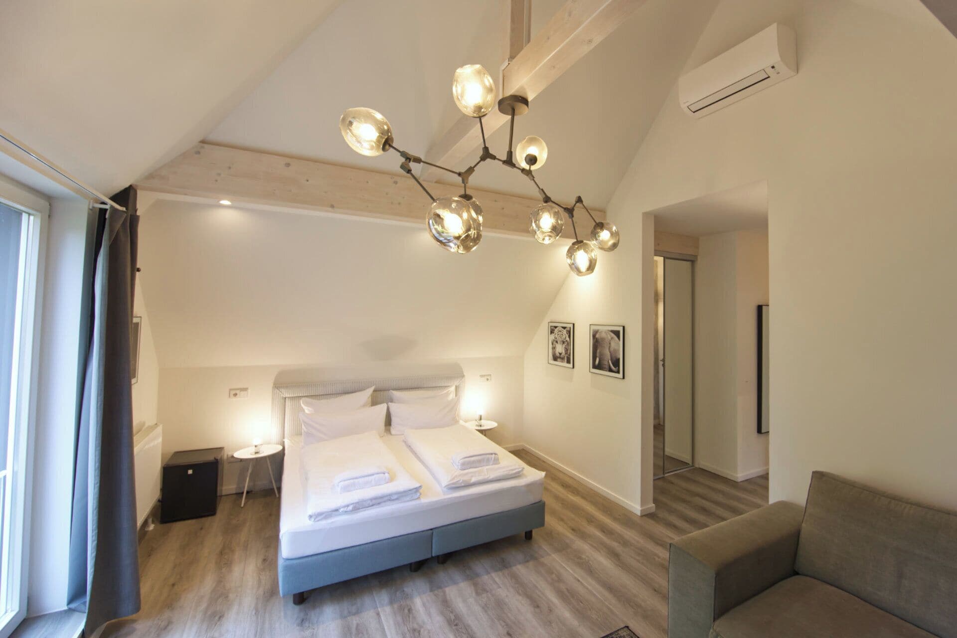 Un dormitorio moderno con una cama grande, una lámpara única y vista al pasillo.