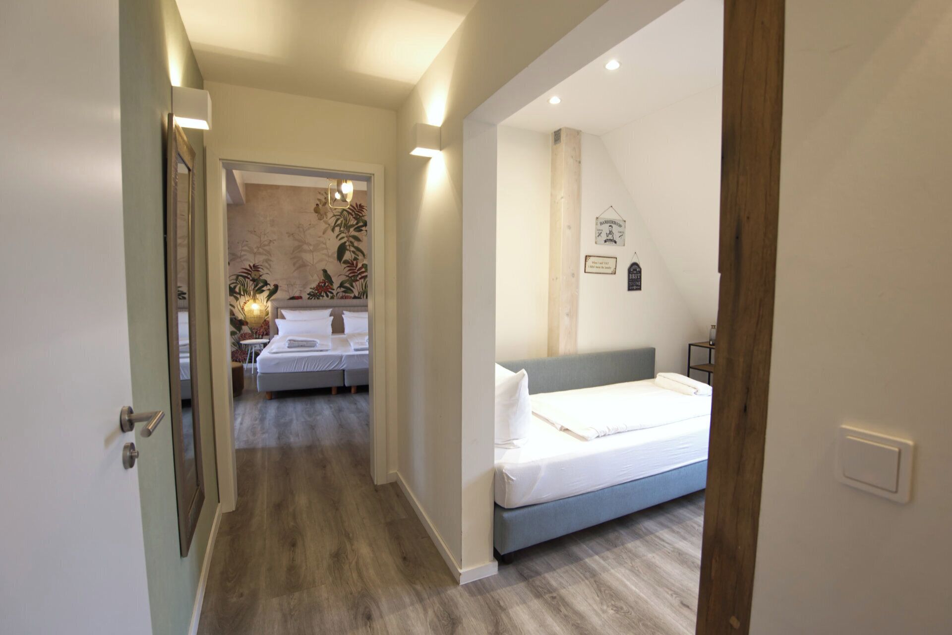 Una habitación de hotel con una cama, una mesita de noche y una lámpara fijada a la pared.