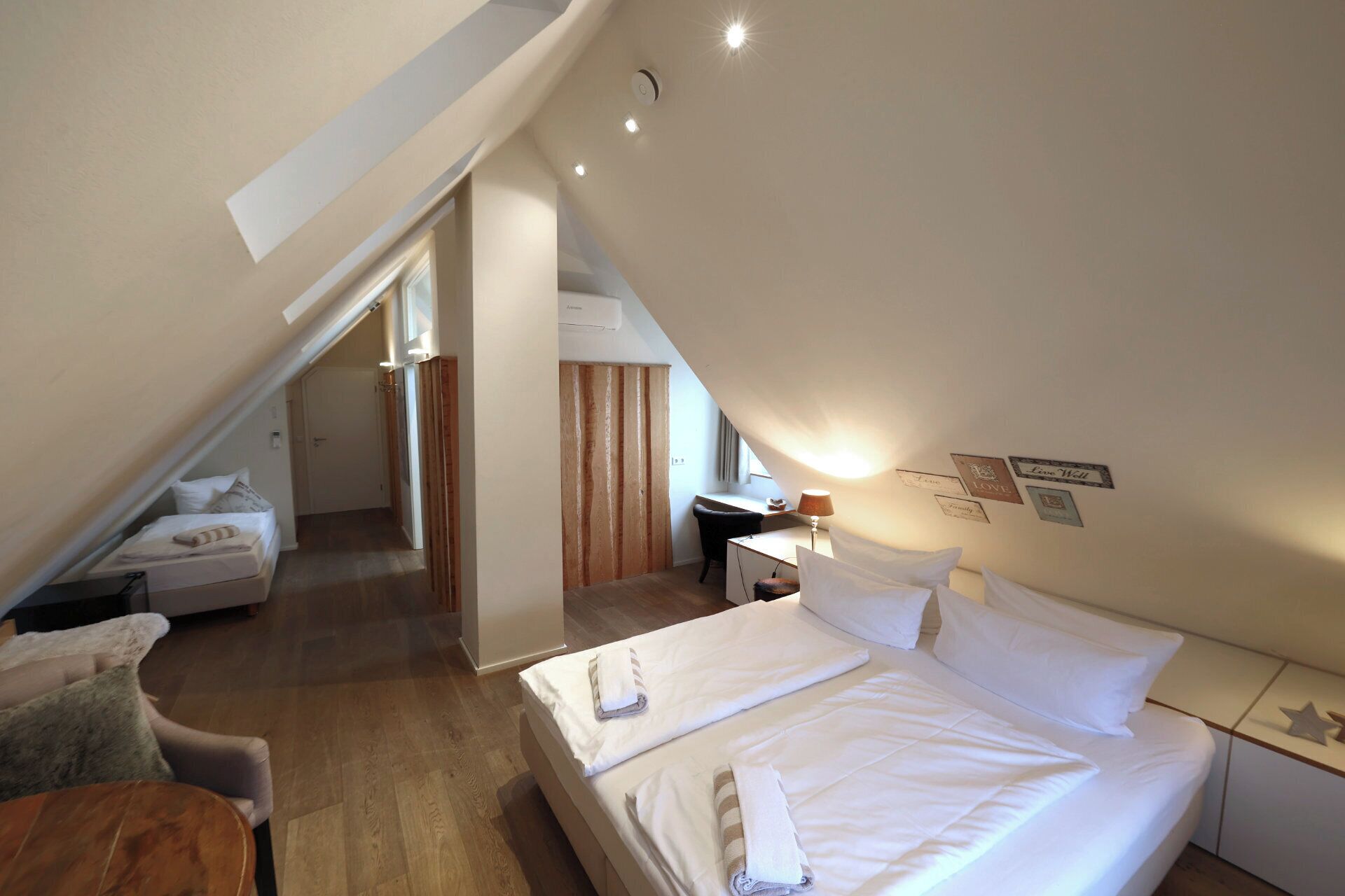 Een slaapkamer met een schuine kap, een bed, een bureau en een stoel.