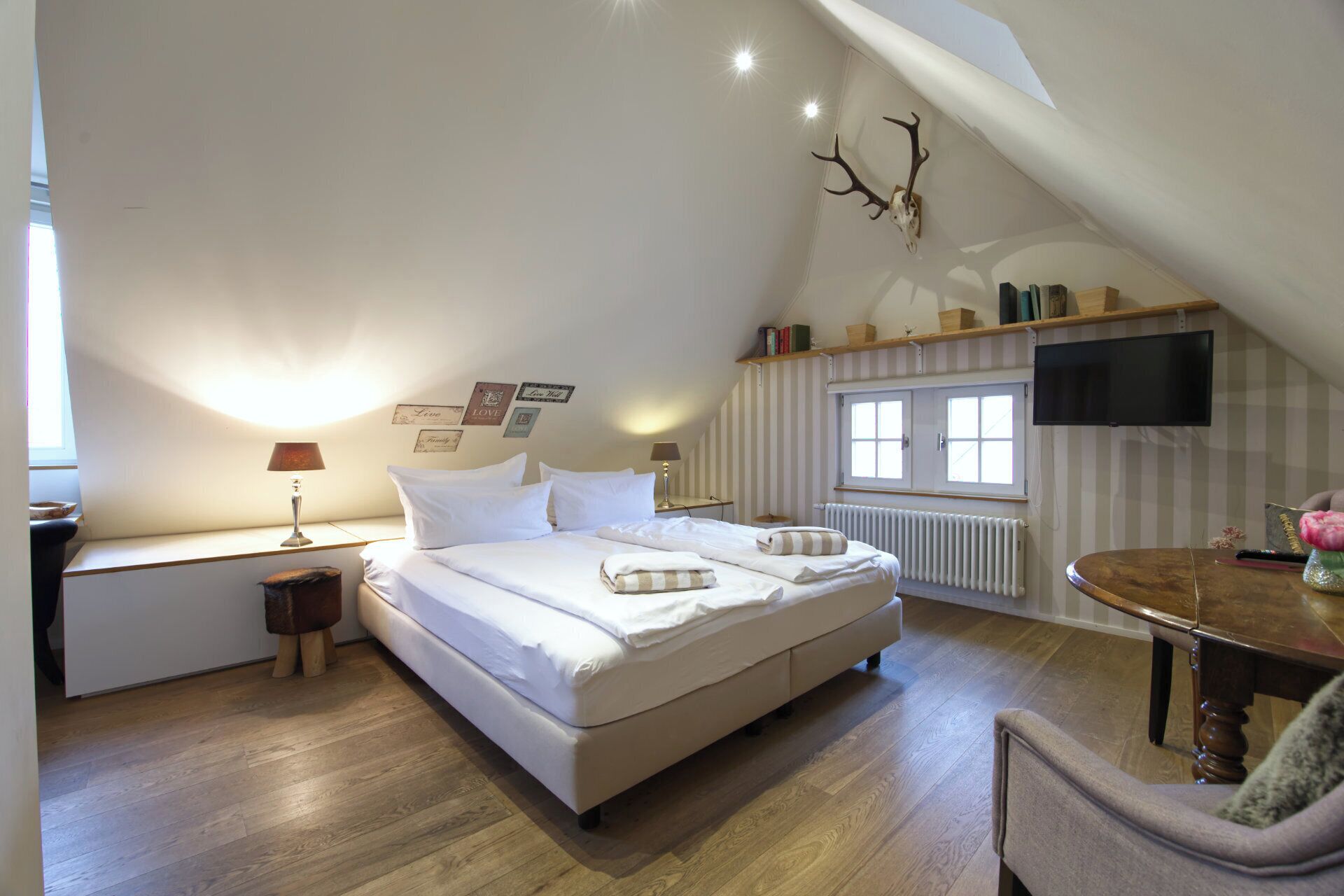 Una camera da letto mansardata accogliente con un letto grande, una scrivania, una sedia e un televisore montato a parete.