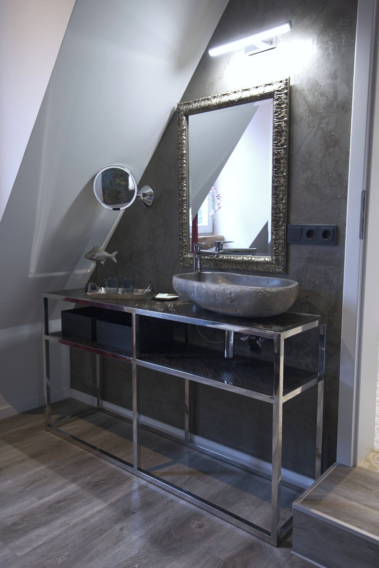 A modern bathroom with a stone sink, a large mirror, and a small round mirror.