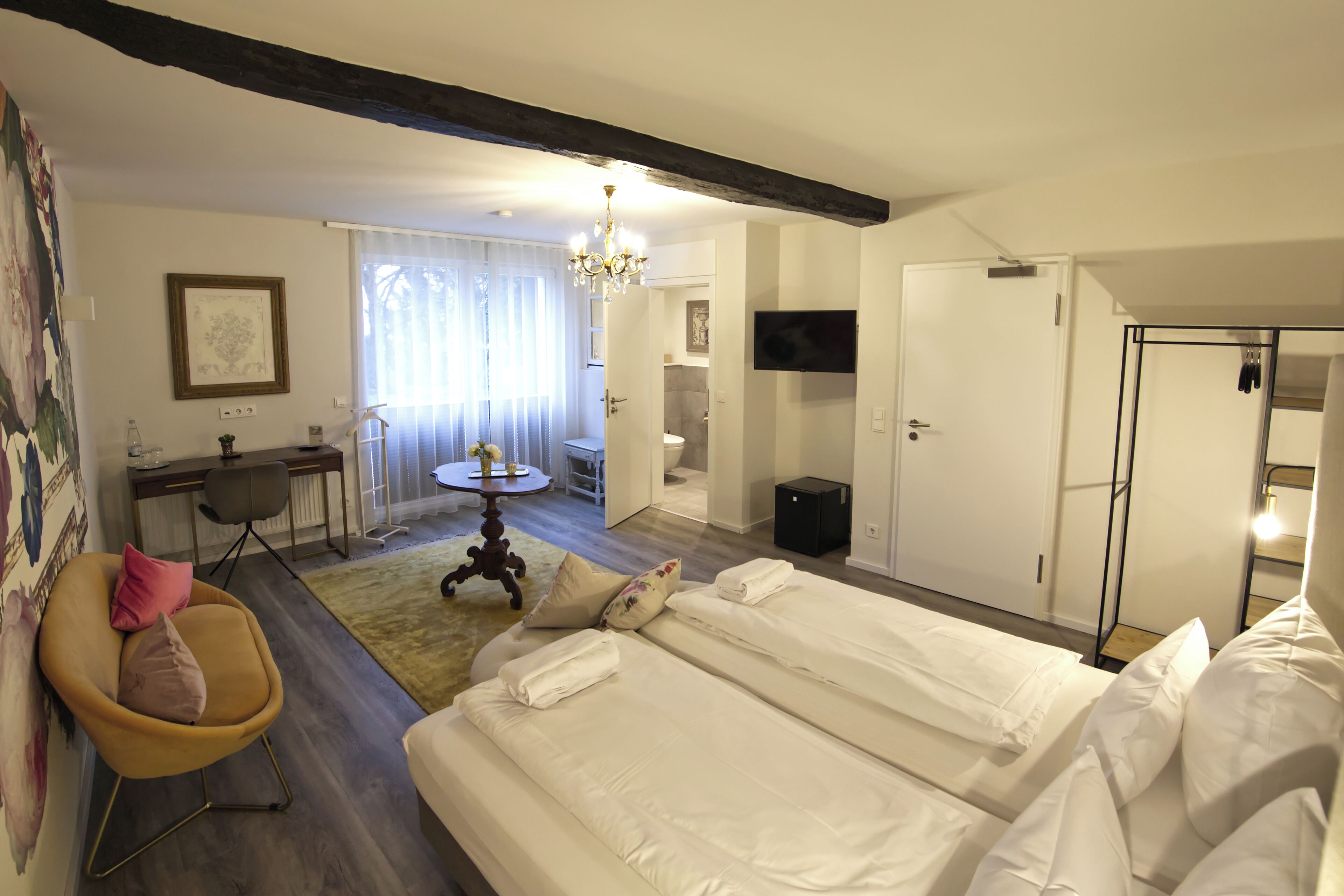 Een hotelkamer met een groot bed, een bureau, een stoel en een kroonluchter.