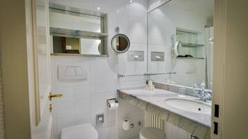 Een moderne badkamer met toilet, bidet en een wastafel met spiegel erboven.