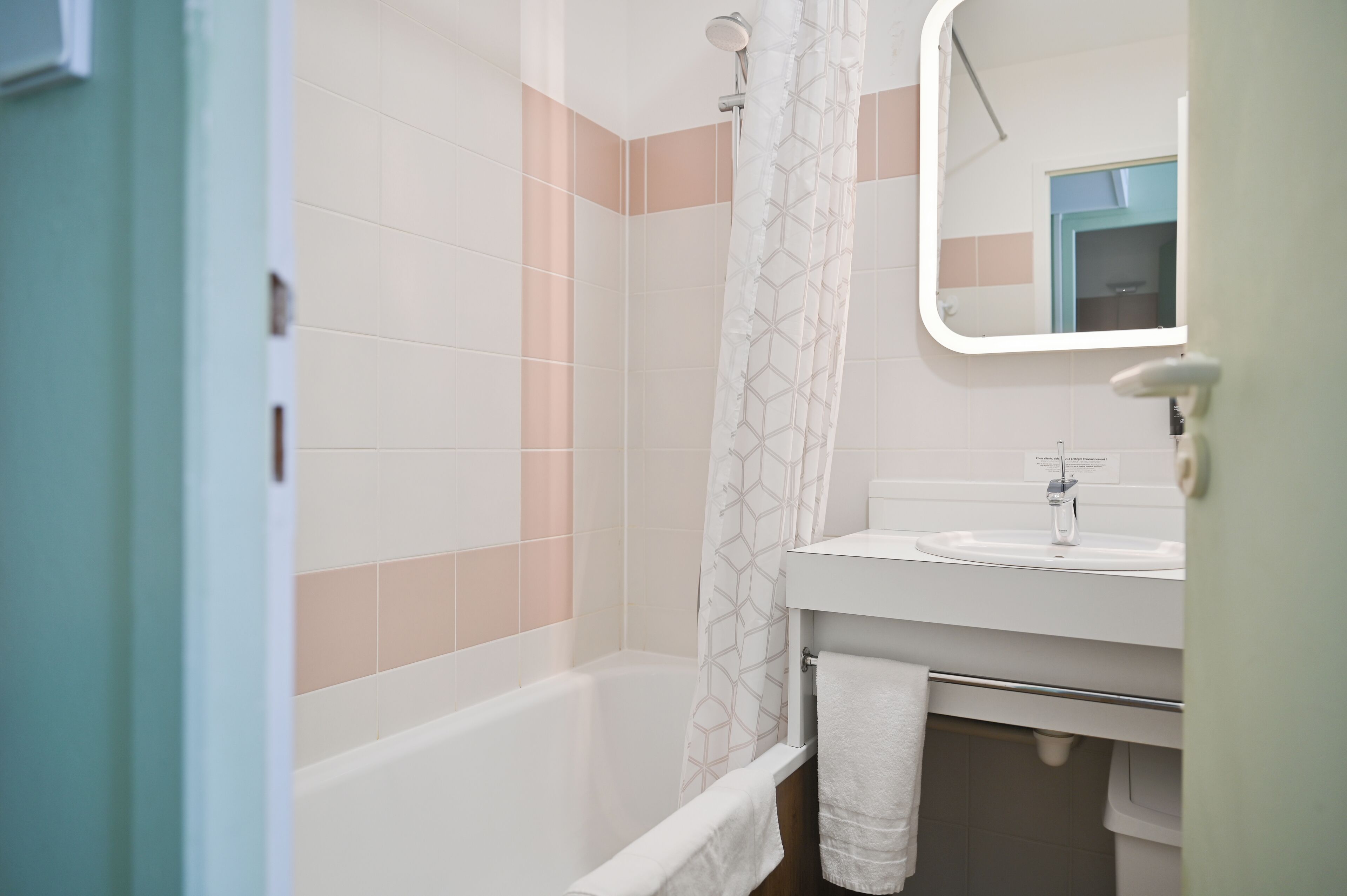 A bathroom with a bathtub, a shower curtain, a sink, and a mirror.