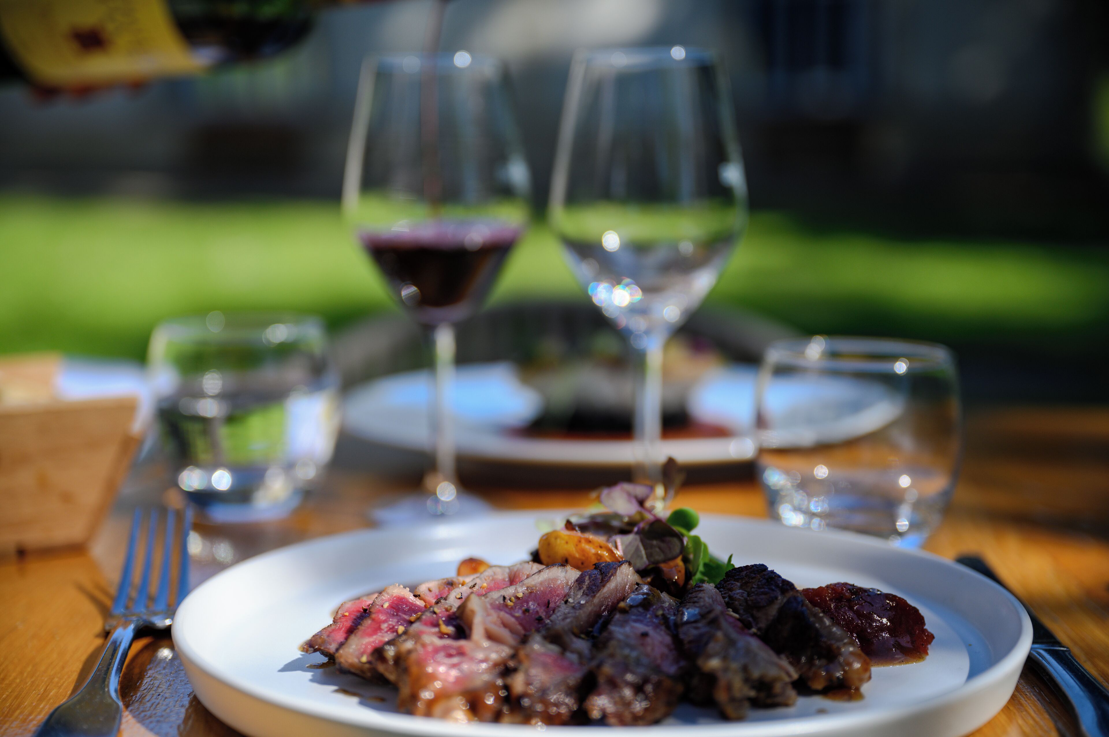 A dining table with a plate of food, wine glasses, and cutlery.
