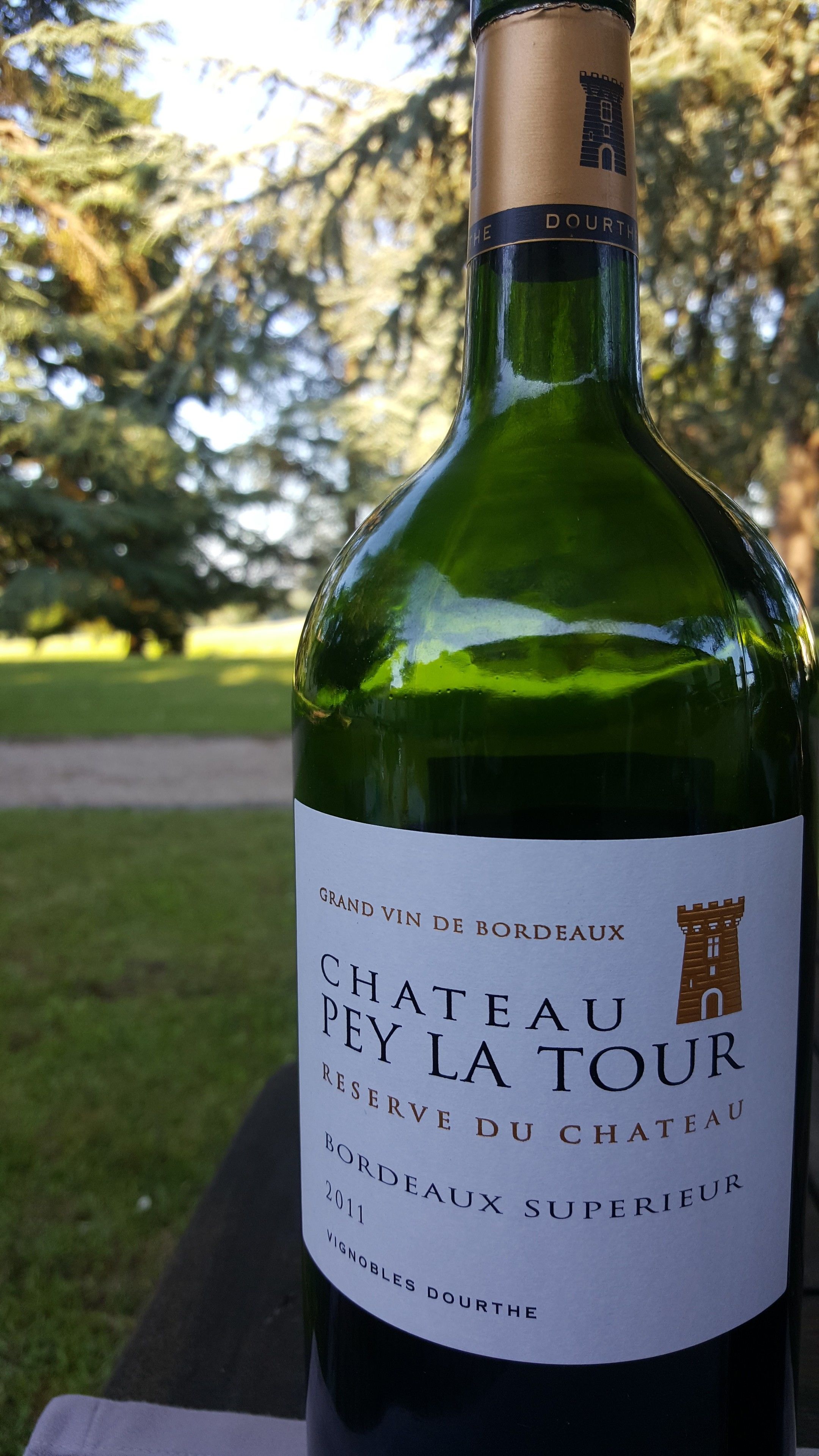 A bottle of Chateau Pey La Tour wine with a label indicating it is a Grand Vin de Bordeaux from 2011.