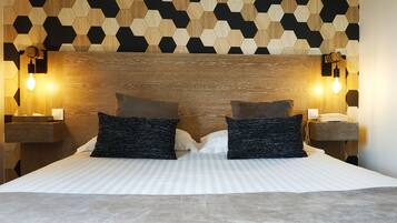 A neatly made bed with two pillows, a wooden headboard, and two wall-mounted nightstands with lamps.