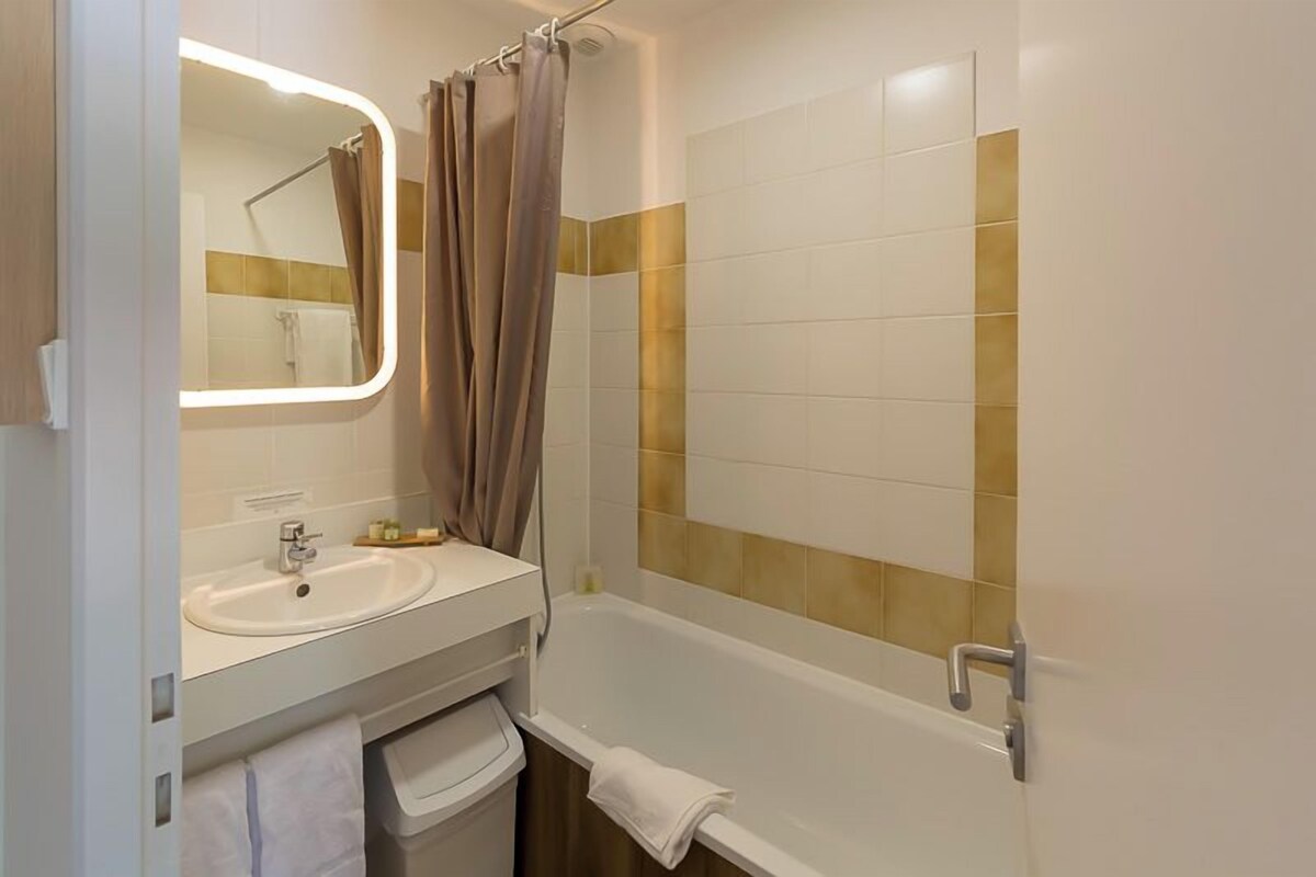 A bathroom with a sink, mirror, shower, and bathtub.