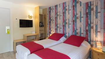 A hotel room with two beds, a desk, a TV, and a wardrobe.