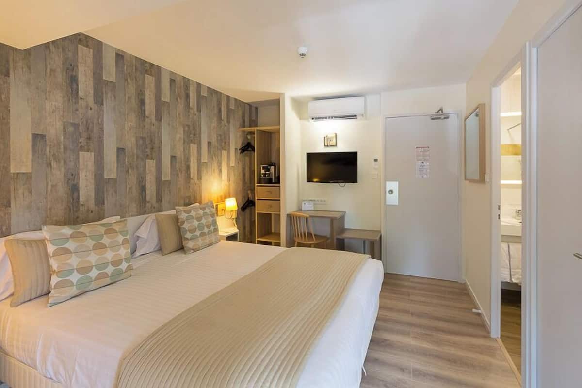 Une chambre d’hôtel avec un grand lit, un bureau, une télévision et une armoire.