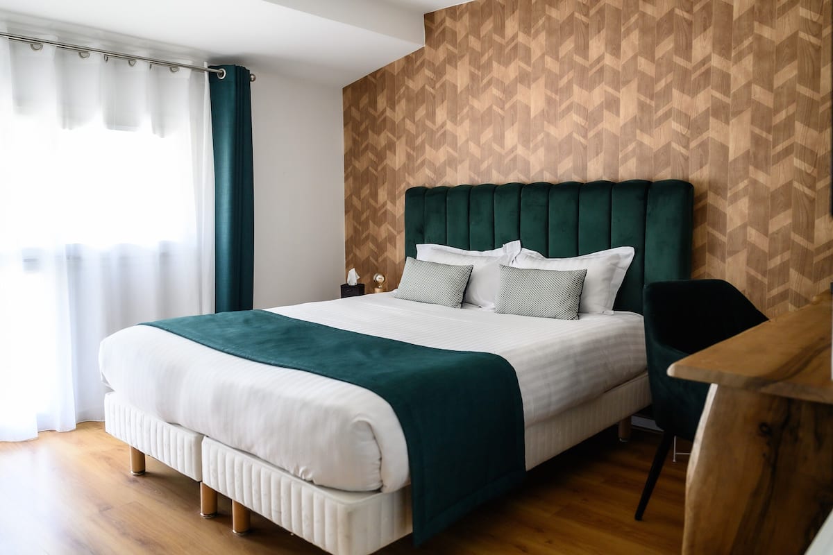 Une chambre moderne avec un grand lit, un mur en bois orné d’un motif en chevrons et un plancher en bois.