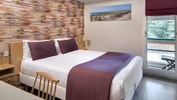 A neatly arranged bedroom with a large bed, a wooden headboard, a wooden side table, a chair, a window with a view of the outdoors, and a wall with a textured pattern.