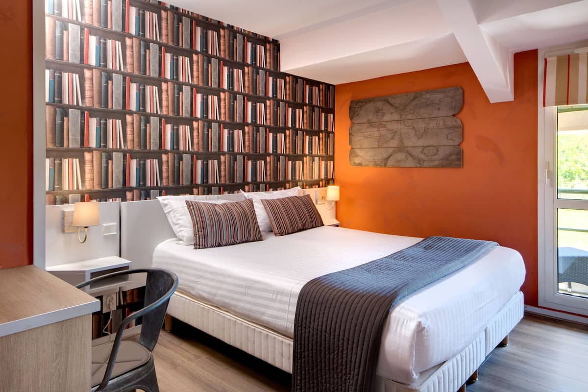 Une chambre avec une grande bibliothèque, un lit avec des oreillers, un bureau et une chaise.