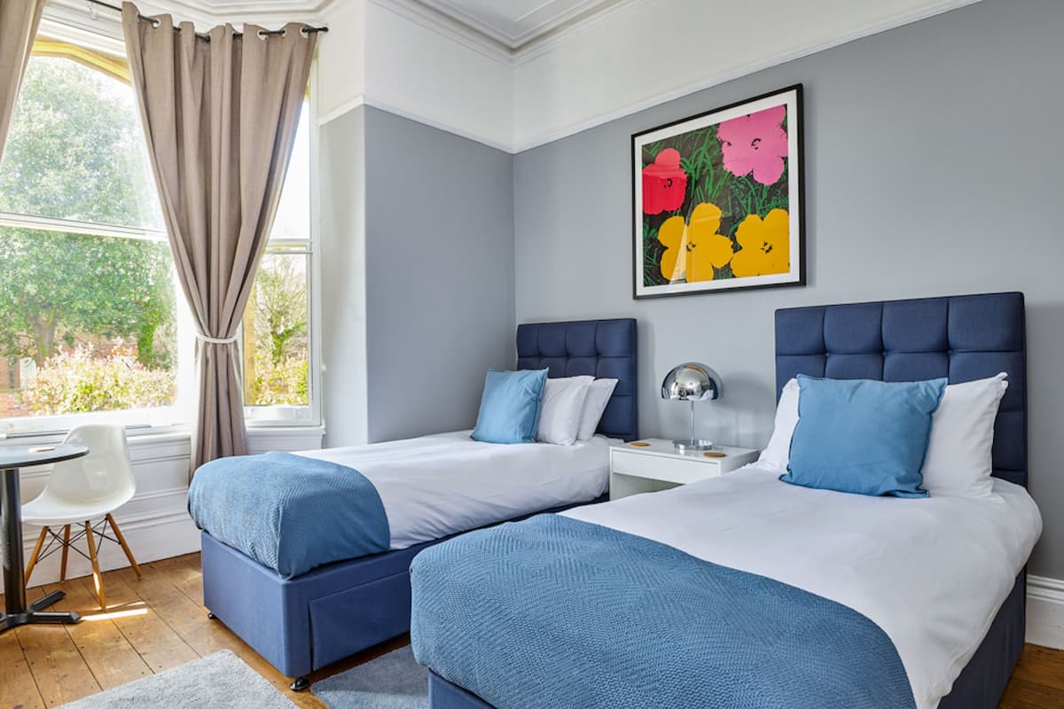 A hotel room with two beds, a desk, and a chair.