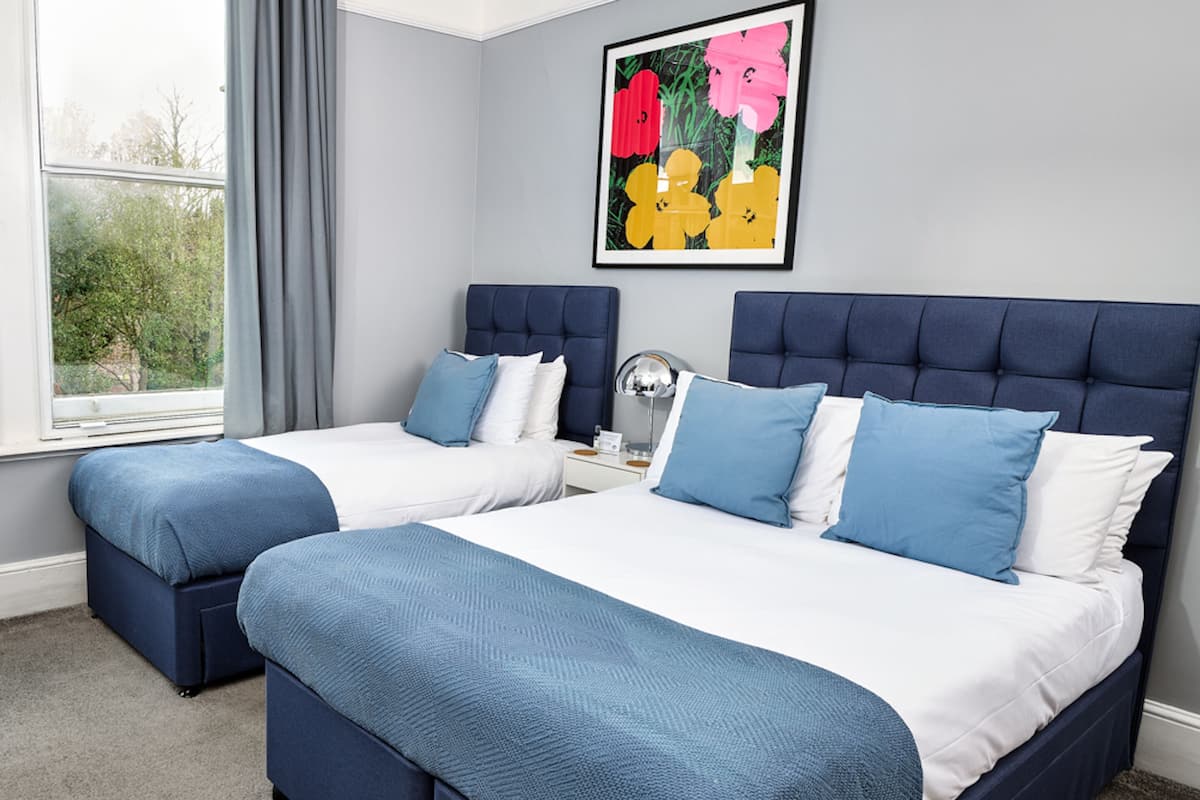 A double bed with a headboard, two bedside tables, and a window with curtains.