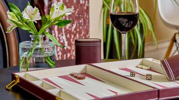 Una mesa con una caja de bombones, una copa de vino tinto y un jarrón con flores blancas.