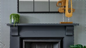 Una chimenea moderna con un revestimiento mural de patrón geométrico, una silla negra y un sillón colgante de madera.