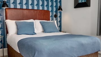 A bed with a wooden headboard, white and blue bedding, and a blue throw blanket.