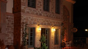A stone building with a patio area, outdoor seating, and a barbecue grill. - Cunda Fora Hotel (Ayvalik)