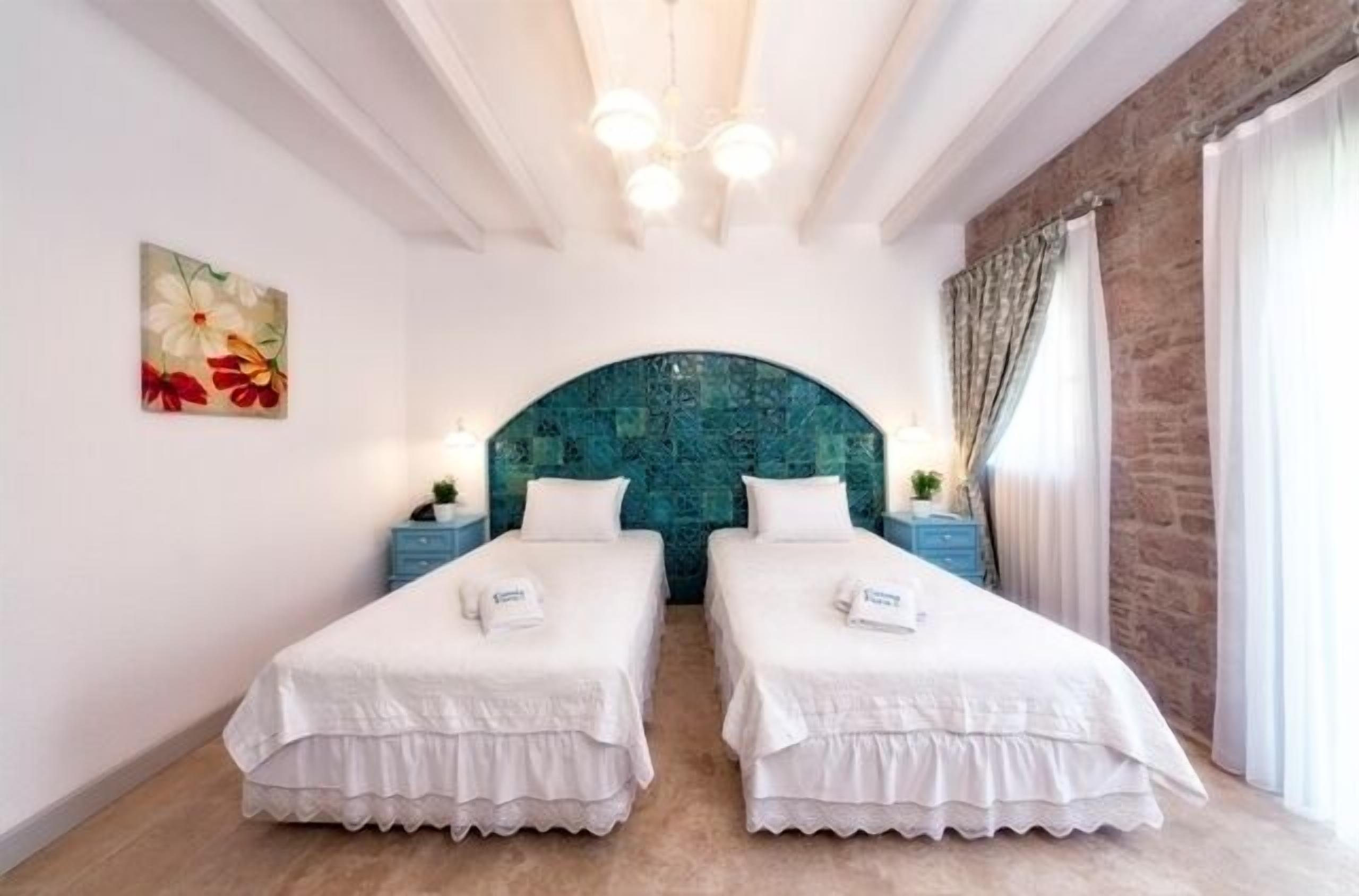 Une chambre avec deux lits, un mur décoratif et un lustre.