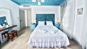 A bedroom with a large bed, a desk, and a chair. There is a door leading to another room. - Cunda Fora Hotel (Ayvalik)
