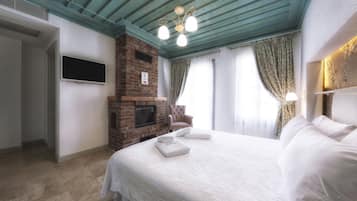 Un dormitorio con chimenea de ladrillo, televisor de pantalla plana, cama con ropa blanca y techo color turquesa.