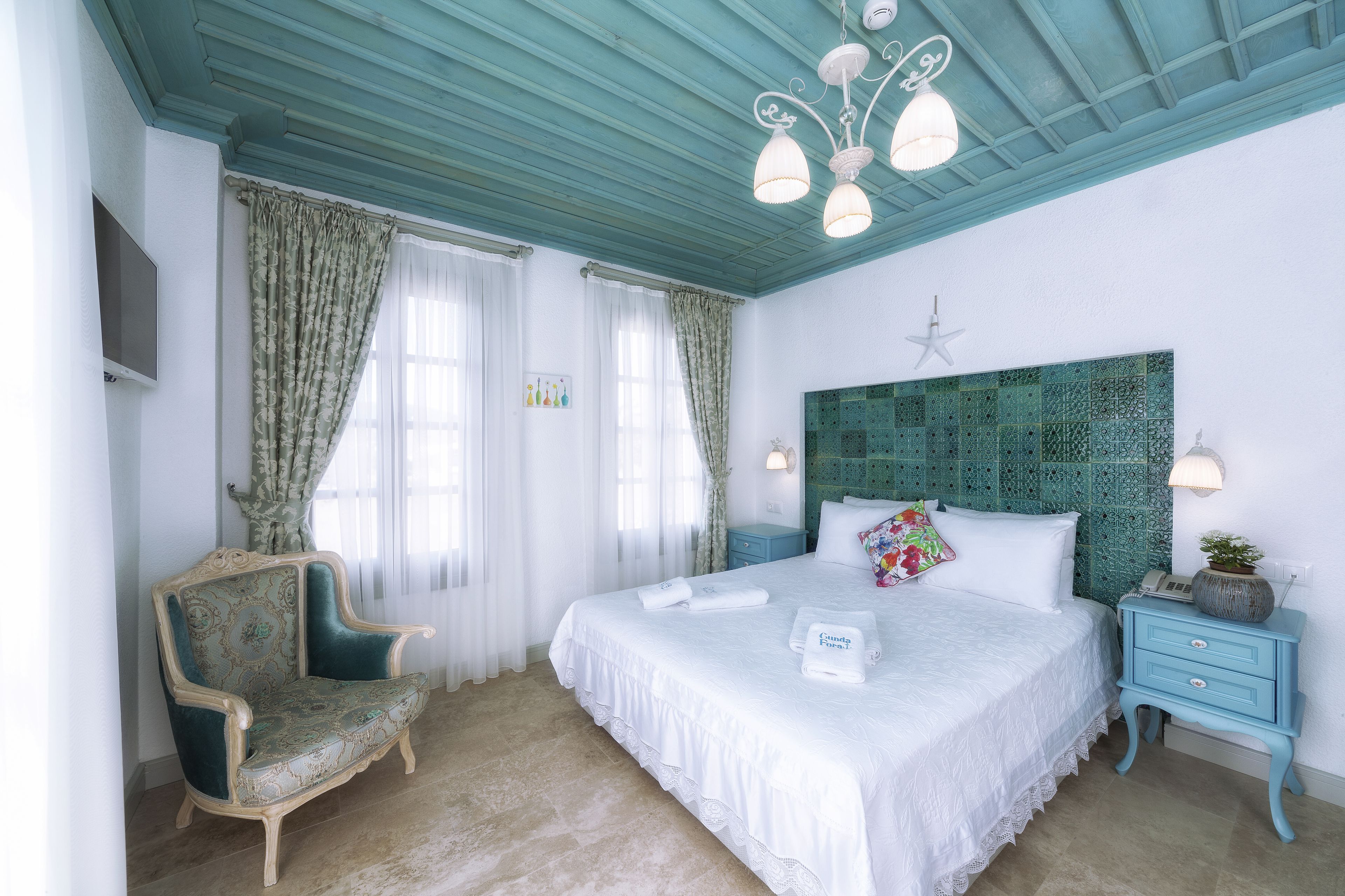 Ein Schlafzimmer mit einem großen Bett, einem Sessel, einem Nachttisch und einem Deckenventilator.