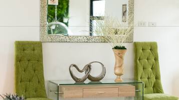 Una habitación con dos sillones tapizados en verde, una mesa de centro de vidrio con base de madera y un objeto decorativo con forma de corazón.