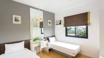 Habitación de hotel con dos camas, un escritorio, una silla, un espejo grande y una ventana con vistas.