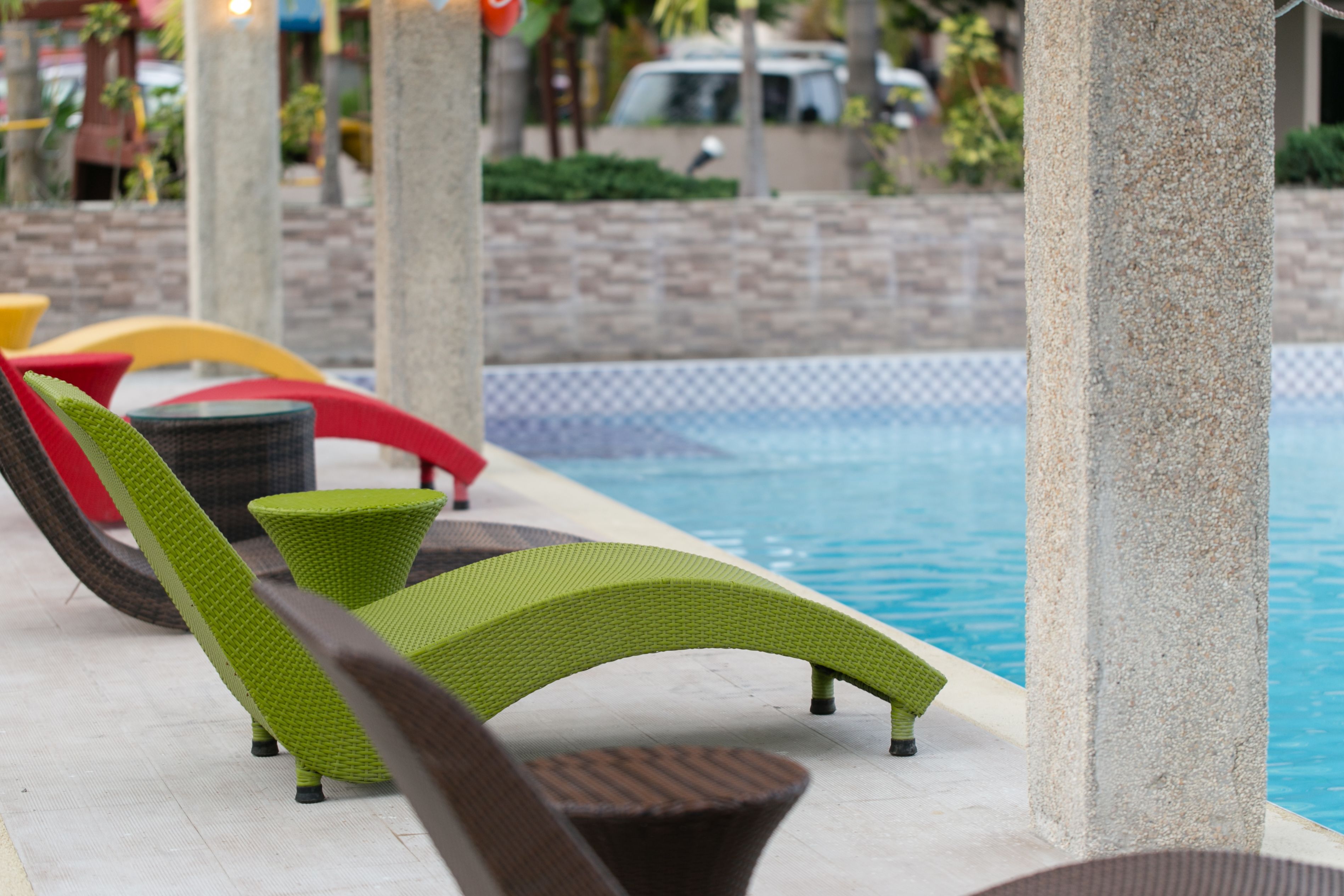 A poolside area with lounge chairs and a stone pillar.